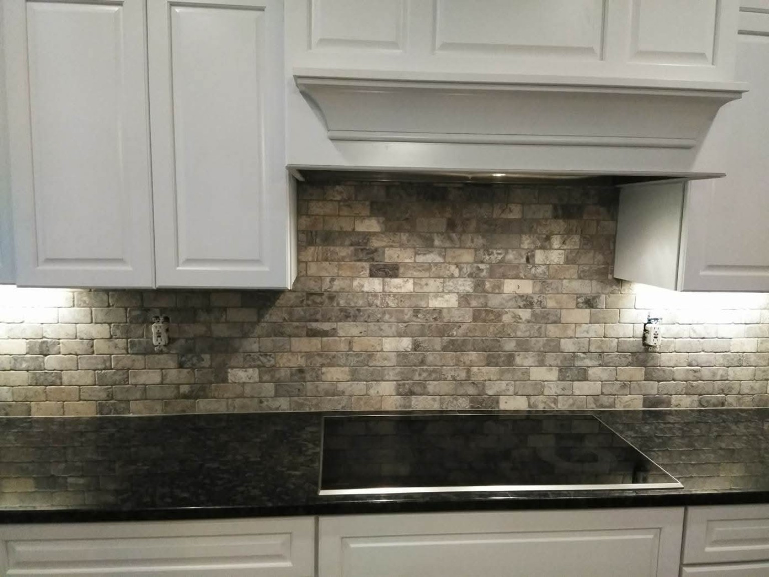 Stone-look kitchen backsplash below white cabinetry