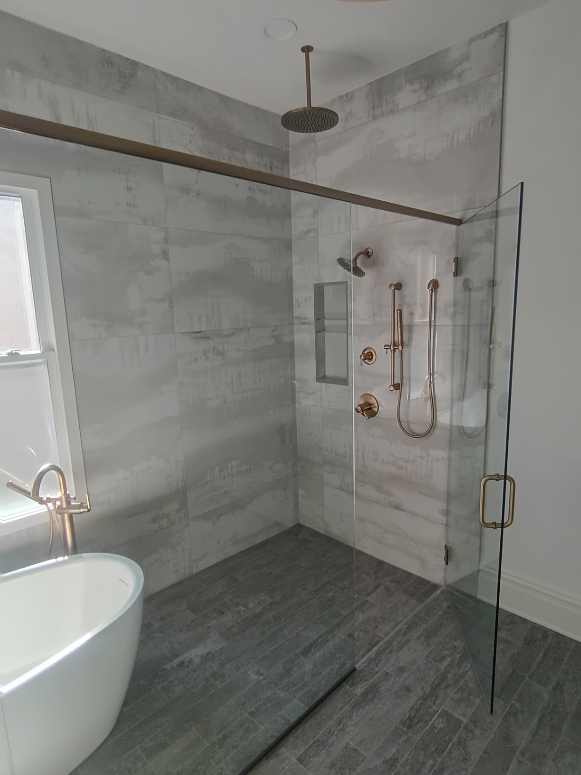 Custom walk-in shower with large-format tile, glass enclosure and bronze fixtures
